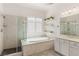 Bright main bathroom featuring a glass shower, soaking tub and a window with plantation shutters at 7340 Orchard Harvest Ave, Las Vegas, NV 89131