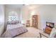 Cozy bedroom with natural light, light walls and carpet, ceiling fan, and a rocking chair beside a bookcase at 7521 Dry Pines Cir, Las Vegas, NV 89129