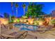 Backyard with a pool, spa, and cozy seating amidst lush landscaping and ambient lighting; ideal for relaxation at 7521 Dry Pines Cir, Las Vegas, NV 89129