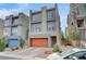 Contemporary gray home featuring an orange garage door, multiple windows, and low maintenance landscaping at 8087 Carpenter Creek Ave, Las Vegas, NV 89113