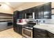 Beautiful kitchen featuring stainless steel appliances, black cabinets, tiled floors, and integrated laundry area at 812 Rio Poco Ct, Henderson, NV 89015