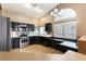 Modern kitchen featuring sleek black cabinetry, tile backsplash, stainless steel appliances, and ample natural light at 812 Rio Poco Ct, Henderson, NV 89015