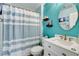 Stylish bathroom featuring turquoise walls, a decorative mirror, and a shower with a striped curtain at 8212 Swallow Falls St, North Las Vegas, NV 89085