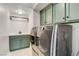Modern laundry room with stylish washer and dryer units, complemented by green cabinets and sleek countertops at 8212 Swallow Falls St, North Las Vegas, NV 89085