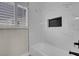 Bright bathroom with marble tiled walls, a window with shutters, and a sleek bathtub at 8232 Ocean Terrace Way, Las Vegas, NV 89128