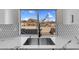 Close up of marble kitchen countertop, stainless steel sink, and tiled backsplash with a view of the backyard at 8232 Ocean Terrace Way, Las Vegas, NV 89128