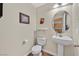 Half bathroom with a pedestal sink, toilet, mirror, and neutral colored walls at 9009 Ochoa St, Las Vegas, NV 89143