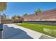 Spacious backyard featuring artificial grass, a brick wall, and a concrete patio at 9413 Steeltree St, Las Vegas, NV 89143