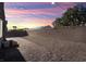 An expansive backyard with a brick-paved walkway, desert landscaping, and string lights at sunset at , North Las Vegas, NV 89031
