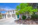 Townhome with tidy landscaping, a two-car garage, and a striking turquoise front door at 1000 Grammy Dr, Las Vegas, NV 89145