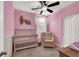 Charming bedroom with pink walls, a white crib, carpet, and a comfortable chair at 1024 Fishing St, Henderson, NV 89011