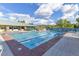 A community pool on a sunny day with lounge chairs, tables, and an adjacent building with beautiful mountain views in the distance at 1991 High Mesa Dr, Henderson, NV 89012