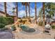 Outdoor oasis featuring a rock waterfall spa with mature palms, lush greenery, and a patio seating area at 2544 Sundew Ave, Henderson, NV 89052