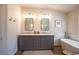 Bathroom featuring a dual sink vanity with marble countertops, soaking tub, and stylish mirrors at 2544 Sundew Ave, Henderson, NV 89052