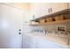 Bright laundry room featuring a side-by-side washer and dryer, overhead cabinets, and shelving at 2544 Sundew Ave, Henderson, NV 89052