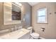 Updated bathroom with modern vanity, fixtures, toilet, mirror, shelving, and a window for natural light at 417 Wisteria Ave, Las Vegas, NV 89107