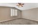 This carpeted bedroom features a vaulted ceiling, a ceiling fan, and a large window for ample natural light at 4411 Wild Honey Ct, Las Vegas, NV 89147