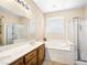 Bright bathroom featuring a double sink vanity, soaking tub, and separate glass enclosed shower at 5521 Moss Landing St, North Las Vegas, NV 89031