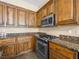 Traditional kitchen featuring stained wood cabinets and granite countertops plus modern stainless appliances at 5521 Moss Landing St, North Las Vegas, NV 89031