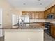 Open kitchen design with island, stainless appliances, granite counters, and stained wood cabinets at 5521 Moss Landing St, North Las Vegas, NV 89031