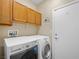 Functional laundry room featuring a modern washer and dryer with wood cabinets for storage at 5521 Moss Landing St, North Las Vegas, NV 89031
