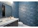 Modern powder room with decorative blue wallpaper, sleek vanity, and silver accents at 600 Quail Covey Road, Henderson, NV 89002