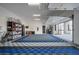 Spacious three-car garage showcasing a blue and gray tiled floor, storage racks, and an electric vehicle charger at 600 Quail Covey Road, Henderson, NV 89002