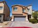 Two-story home featuring a gray two-car garage, desert landscaping, and a charming flower bush at 7057 Millers Run St, North Las Vegas, NV 89084