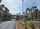 The neighborhood entrance features mature palm trees, a tile roof and a welcome sign for residents and guests at 7115 S Durango Dr # 208, Las Vegas, NV 89113