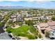 Wide aerial view of a suburban neighborhood with green spaces, palm trees, and mountain backdrop at 7857 Midnight Ride St, Las Vegas, NV 89131