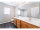 Bathroom with wood cabinets, dual sinks, large mirror, and modern fixtures at 7857 Midnight Ride St, Las Vegas, NV 89131