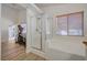 Bathroom featuring walk-in shower, tub, and wood-look floors, adjacent to a bedroom with exercise equipment at 8041 Villa Rosarito St, Las Vegas, NV 89131