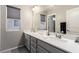 Modern bathroom with a double sink vanity with a gray cabinet, a large mirror, and a window with privacy shades at 813 Bluebird Hill Ave, North Las Vegas, NV 89084