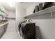 This laundry room features shelving, a front loading washer and dryer, and tile flooring at 813 Bluebird Hill Ave, North Las Vegas, NV 89084