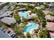 Scenic aerial view of community pool area featuring multiple pools, spa, and lounging areas amid lush landscaping and mature trees at 9077 Creed Mountain Pl, Las Vegas, NV 89178
