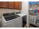 Well-organized laundry room with washer, dryer, storage cabinets, and shelving for supplies at 9077 Creed Mountain Pl, Las Vegas, NV 89178