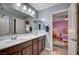 Bathroom features dual sinks, wood cabinets, and a view into a bright, purple themed bedroom at 917 Pomander Point Pl, Henderson, NV 89012