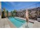 Beautiful pool surrounded by lush greenery, featuring a rock wall and clear blue sky at 917 Pomander Point Pl, Henderson, NV 89012