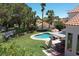 Stunning backyard featuring a lush lawn, sparkling pool, mature trees, and covered patio area at 9921 Heffner Hills Cir, Las Vegas, NV 89117