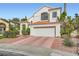 Inviting two-story home featuring a white stucco facade, clay tile roof, brick-patterned driveway, and tidy landscaping at 9921 Heffner Hills Cir, Las Vegas, NV 89117