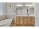 Bathroom featuring dual sinks, vanity, framed mirrors, tub and wood-look tile floors at 11249 Revelry Ln, Las Vegas, NV 89138