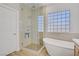Modern bathroom featuring a glass-enclosed shower, soaking tub, and a privacy glass block window at 11249 Revelry Ln, Las Vegas, NV 89138