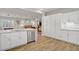 Bright kitchen featuring stainless steel appliances, white cabinetry, wood look floors, and an open view to the living area at 11249 Revelry Ln, Las Vegas, NV 89138