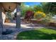 This landscaped backyard features an immaculate lawn, mature trees, and a covered patio with lounge chairs at 1153 Mesa Verde Run, Mesquite, NV 89027
