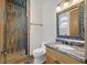 Beautiful bathroom featuring granite countertop, decorative mirror, stone-look tiles in shower, and stylish fixtures at 12 Via Ravello, Henderson, NV 89011