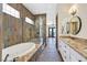 Bathroom showcasing a soaking tub, glass enclosed shower, dual sinks, and decorative stone floors at 12 Via Ravello, Henderson, NV 89011