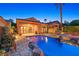 Inviting outdoor pool area with a covered patio, BBQ, and beautiful desert landscaping at dusk at 12 Via Ravello, Henderson, NV 89011