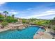 Backyard pool and patio with rock features and lush landscaping, set against a golf course and clear blue sky at 12 Via Ravello, Henderson, NV 89011