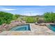 Backyard pool and spa with rock features and lush landscaping, set against a golf course and clear blue sky at 12 Via Ravello, Henderson, NV 89011