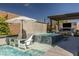Backyard pool with a waterfall feature, lounge chairs, and covered seating area with fireplace at 12024 Girasole Ave, Las Vegas, NV 89138